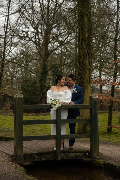Bruidsstel op een brug in een bosrijke omgeving, omringd door bomen.